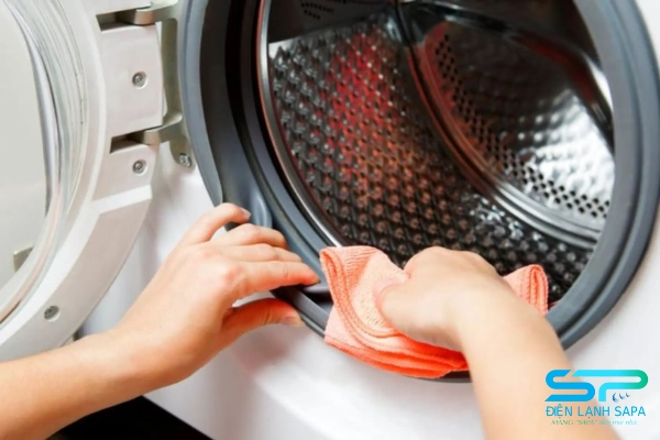 Lau chùi bề mặt ngoài và trong cửa máy giặt để loại bỏ bụi bẩn